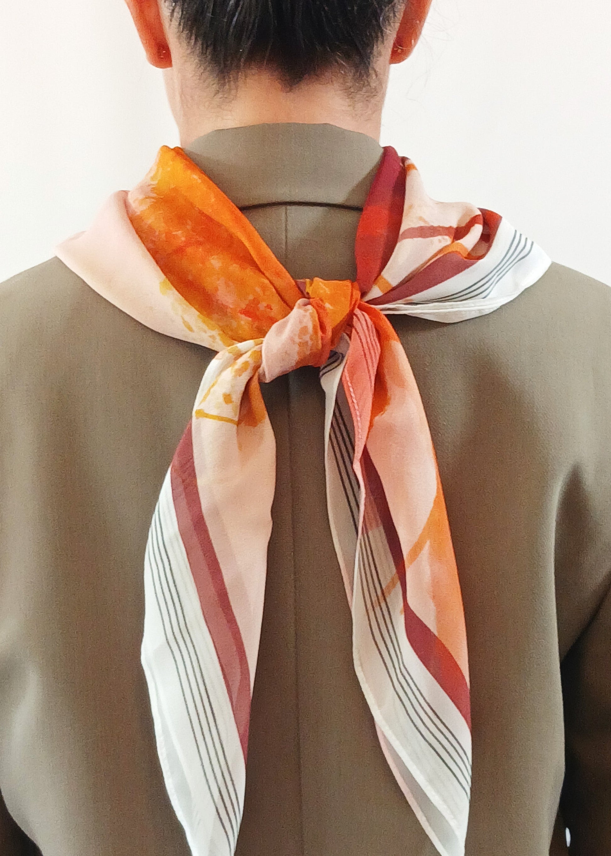 Person wearing a patterned scarf on a plain background
