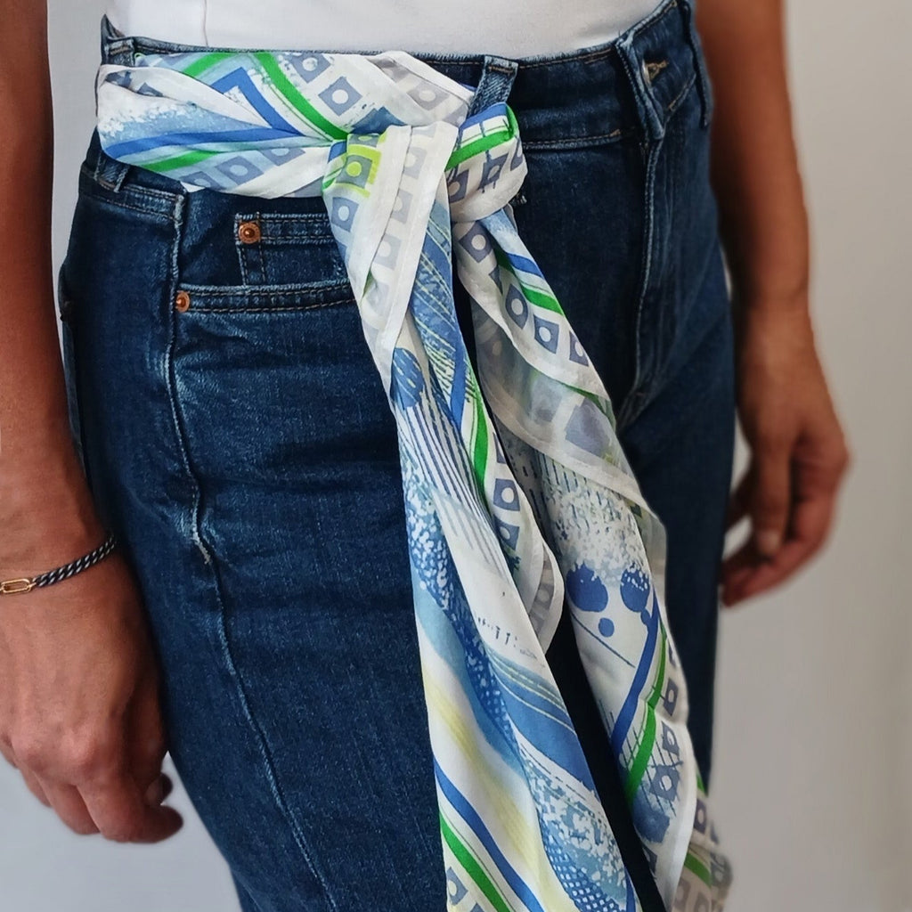 Person wearing a patterned scarf around their waist with a plain background